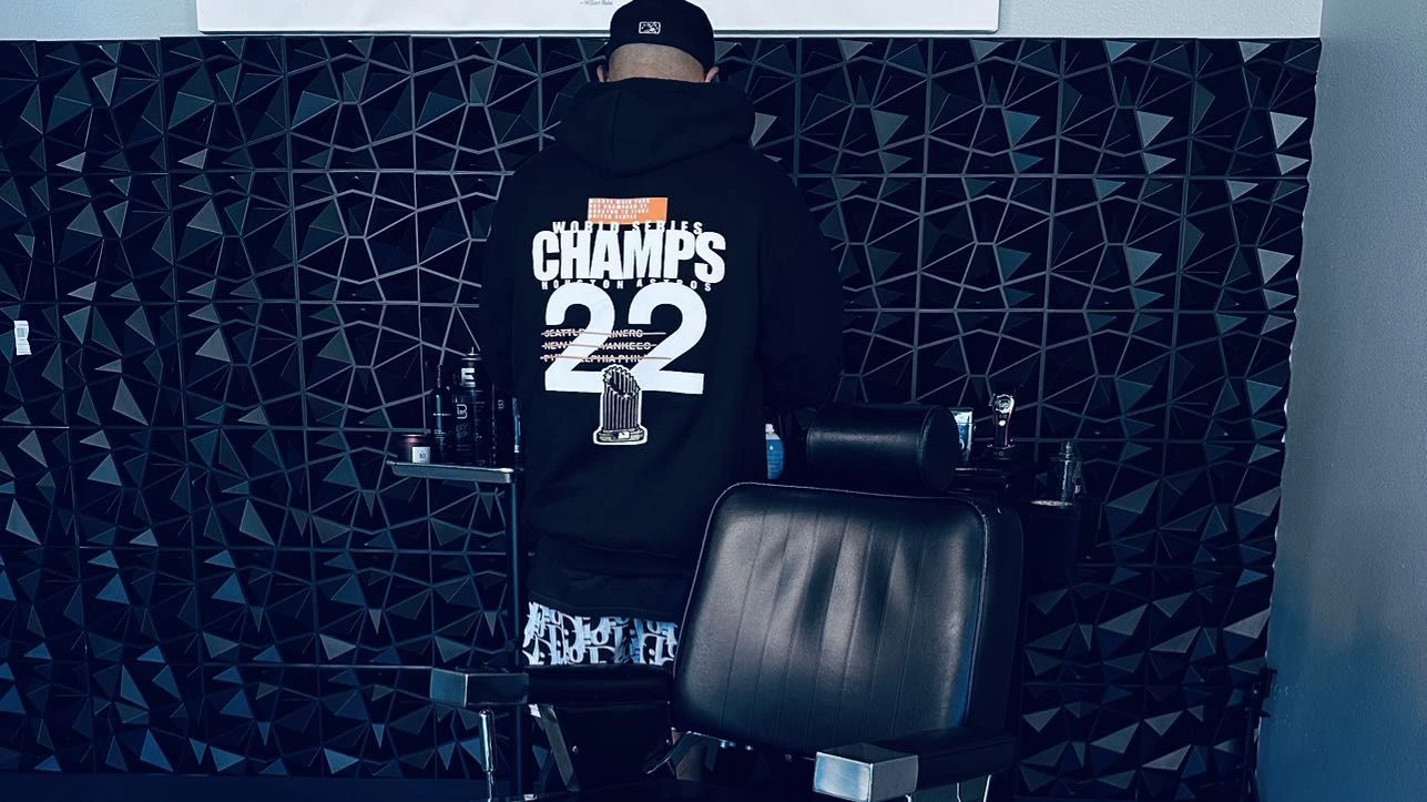 Hector Cardenas in The Premier Barber Studio, with a barber chair and dark textured studio walls