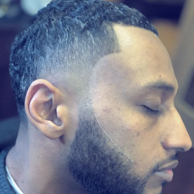 Curly top with a skin fade and defined beard